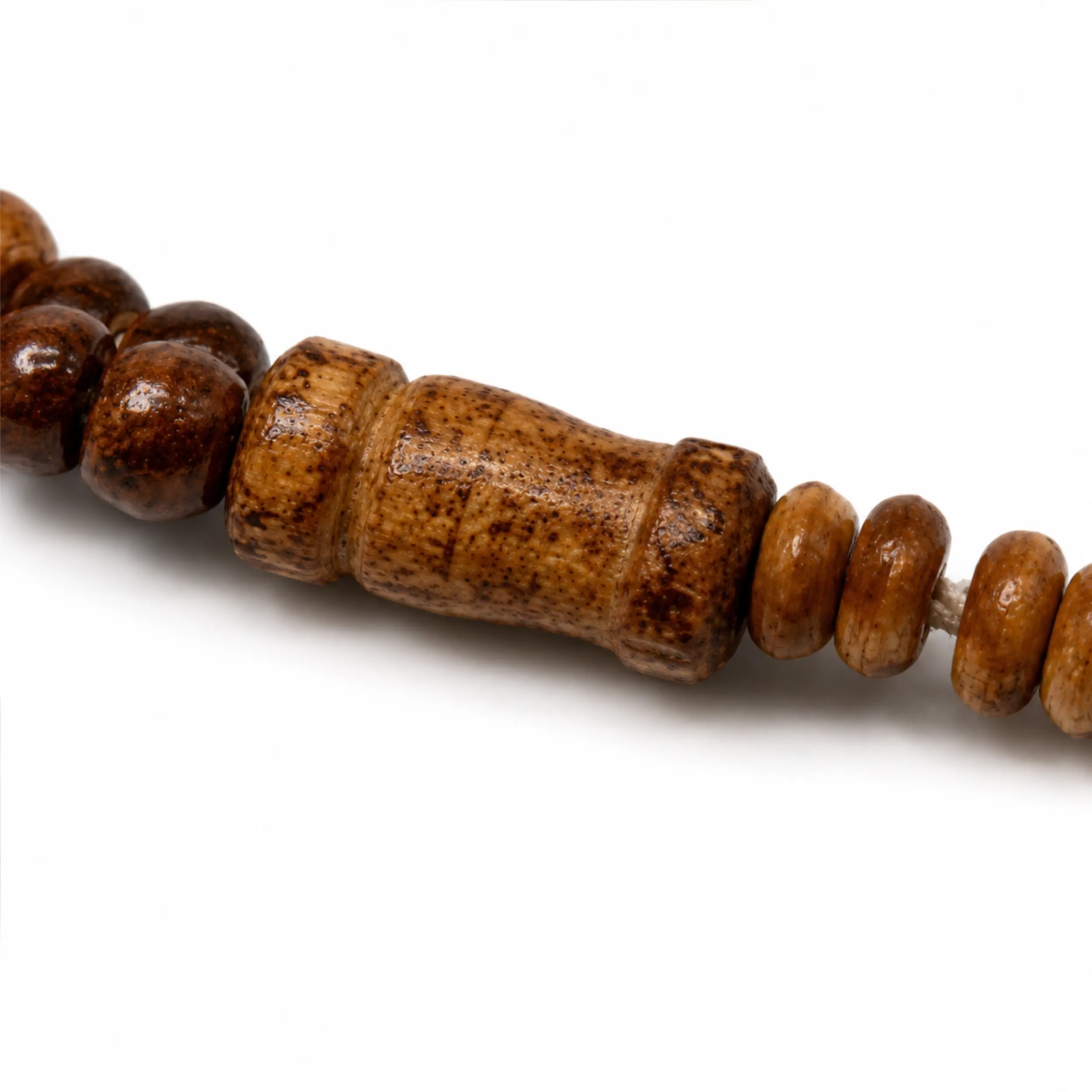 Detailaufnahme des glatten Holzverbindungselements und der hellen Kordel der Tasbih