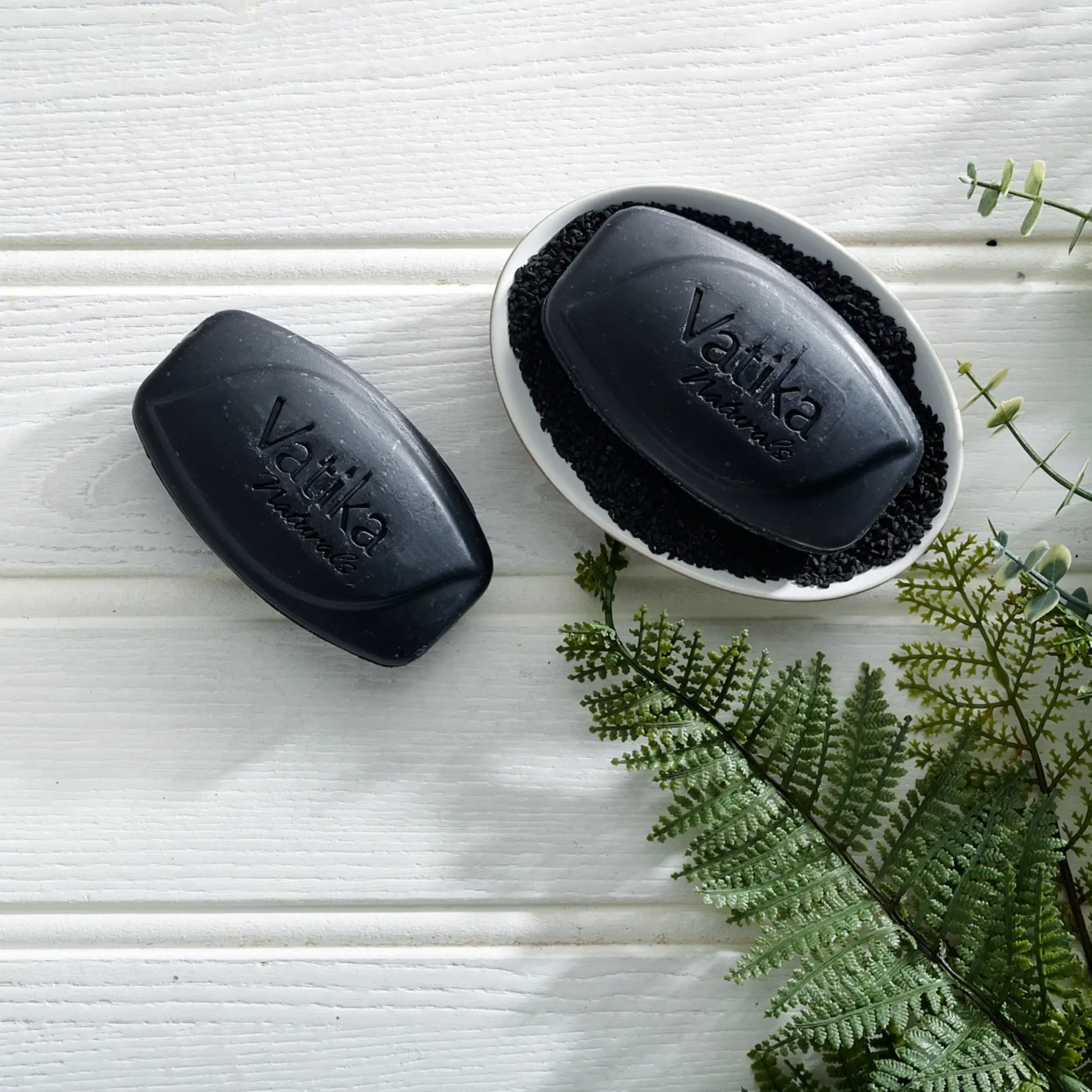 Vatika Blackseed Clarifying Soap Schwarzkümmel Seife 100g in geöffneter Szene mit schwarzer Seife und pflanzlicher Pflegeoptik von Oriental-Style