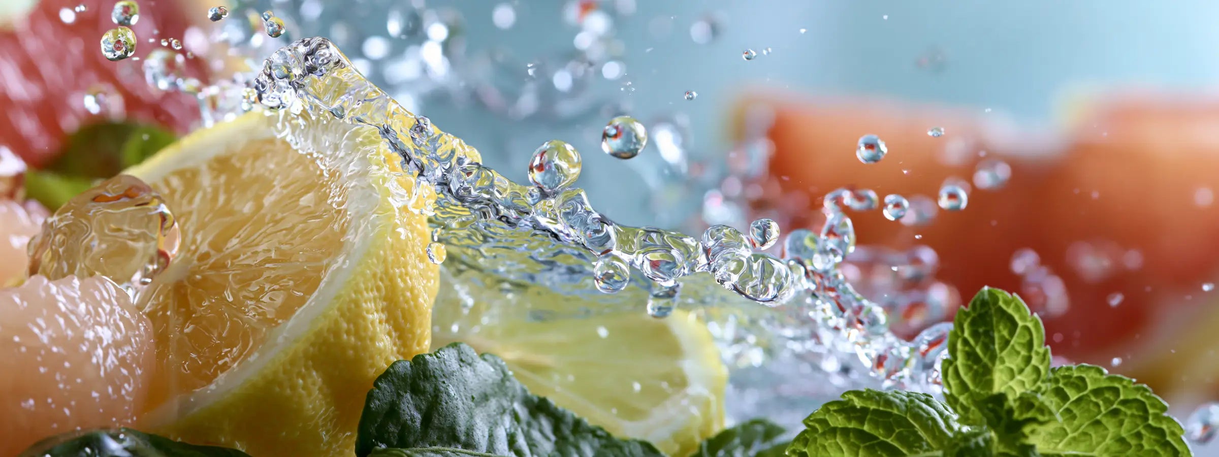 Frische Zitrusfrüchte, Minze und Wassertropfen in Bewegung – Symbolbild für frische Parfüms