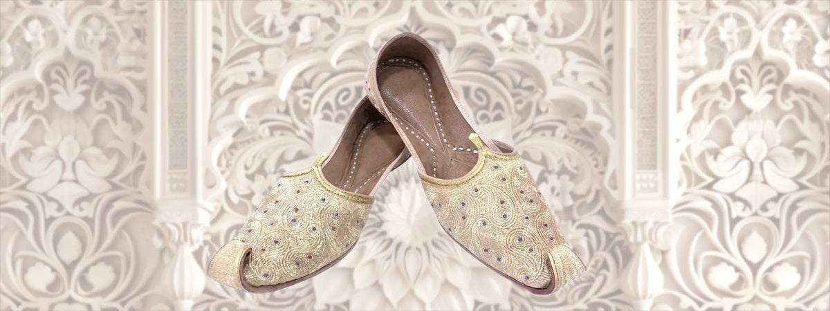 Goldbestickte Khussa-Schnabelschuhe vor floralem Ornamentmuster – Indische Schuhe