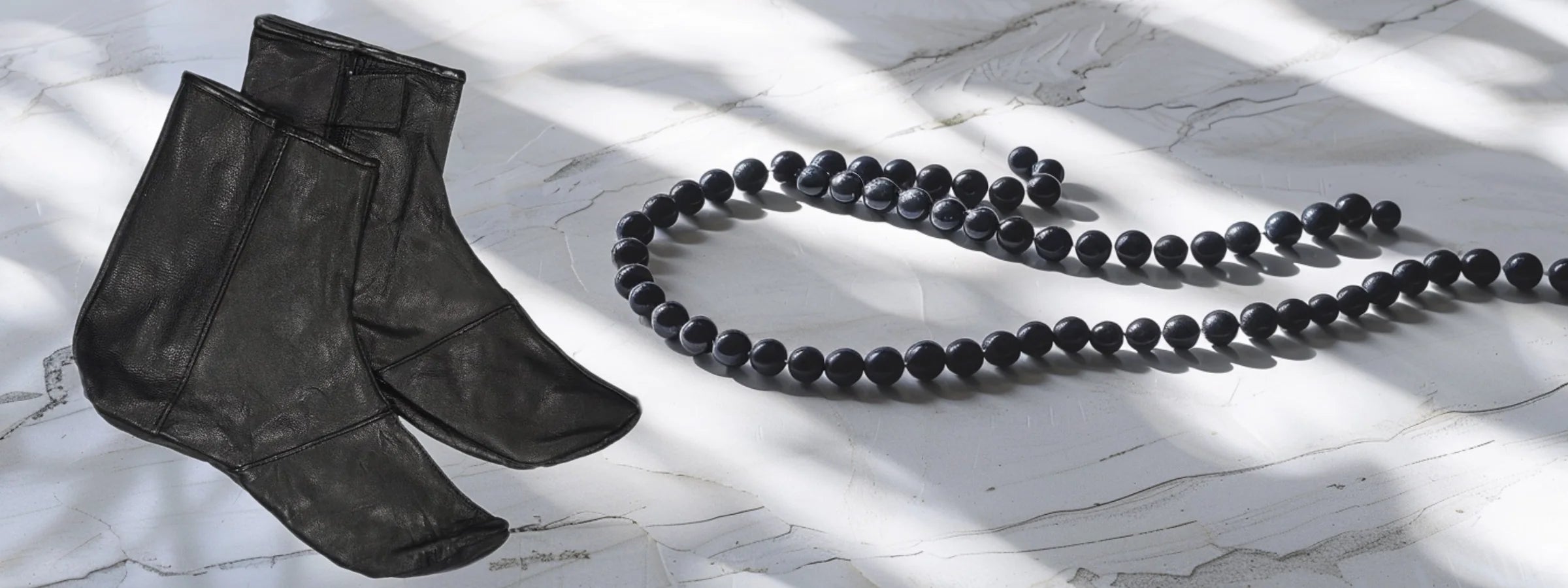 Khuff-Ledersocken und schwarze Tasbih-Gebetskette auf hellem Marmor im Streiflicht – Ihram & Tasbih & Khuff